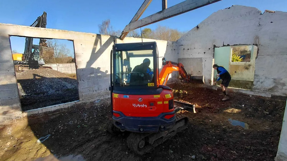 Kubota mini digger excavating inside an existing barn with roof trusses overhead in Ashill, Somerset