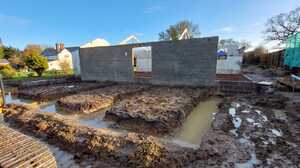 Waterlogged foundation trenches dug in front of barn walls during wet weather in Ashill, Somerset